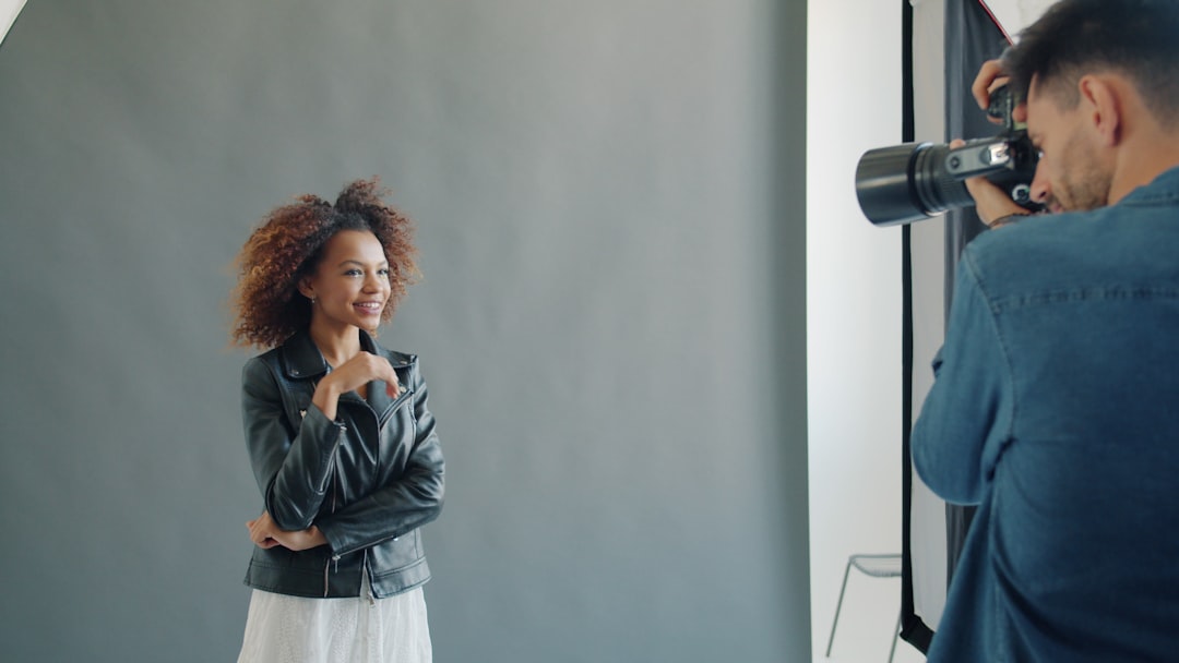 Beautiful Afro-American girl is posing in studio working with photographer indoors wearing trendy fasdhionable garments. Youth and modern lifestyle concept.